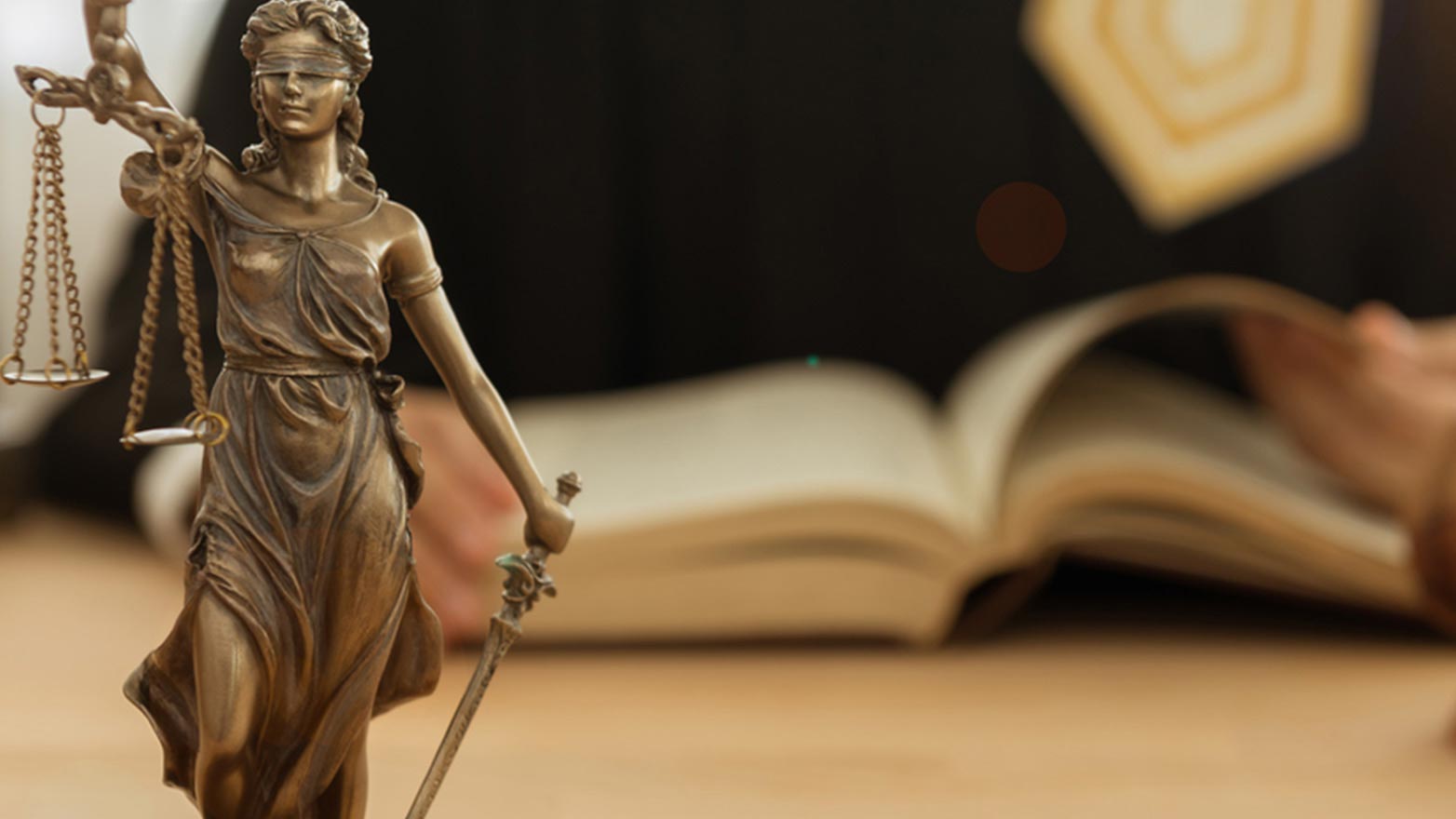 scales of justice figurine on a desk, legal book in background